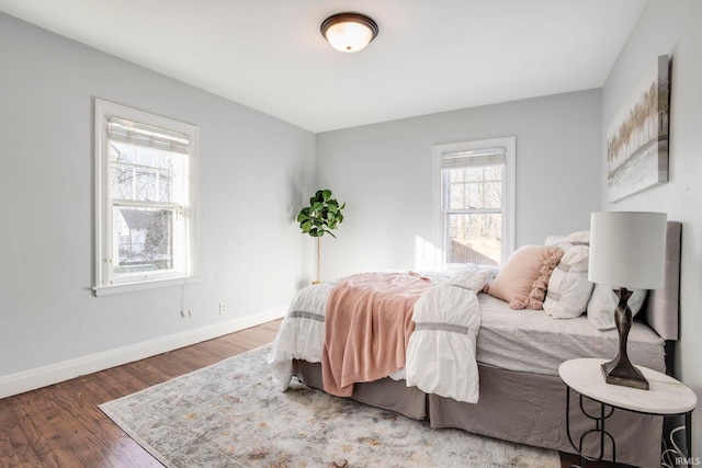 bedroom with dark hardwood / wood-style floors and multiple windows