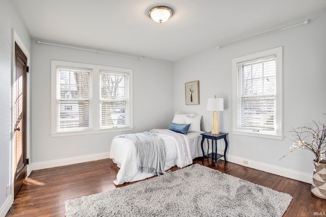 bedroom featuring multiple windows and dark hardwood / wood-style flooring