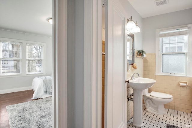 bathroom featuring hardwood / wood-style floors, toilet, and tile walls