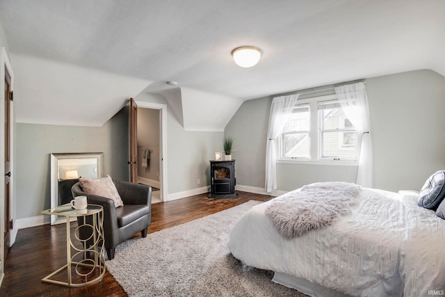 bedroom with lofted ceiling, a wood stove, and dark wood-type flooring