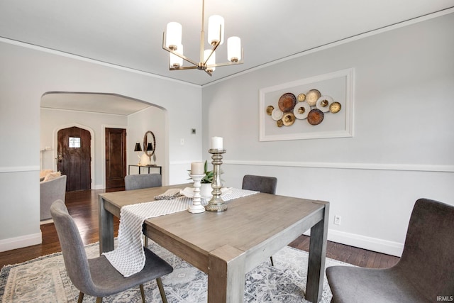 dining area featuring dark hardwood / wood-style floors, ornamental molding, and a notable chandelier