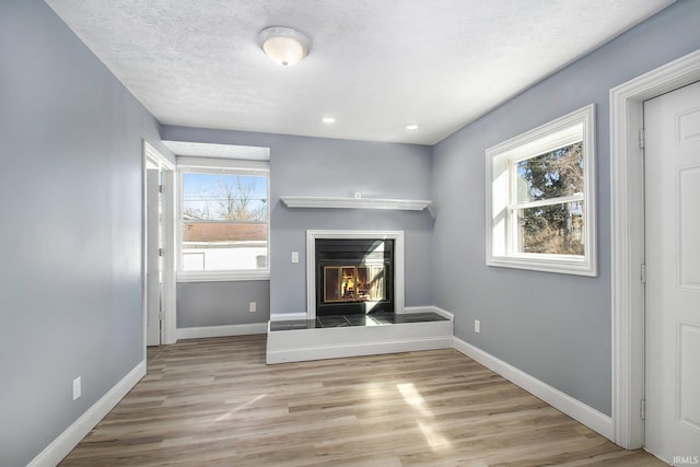 unfurnished living room with light hardwood / wood-style floors and a textured ceiling