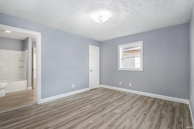 unfurnished room with a textured ceiling and light hardwood / wood-style floors