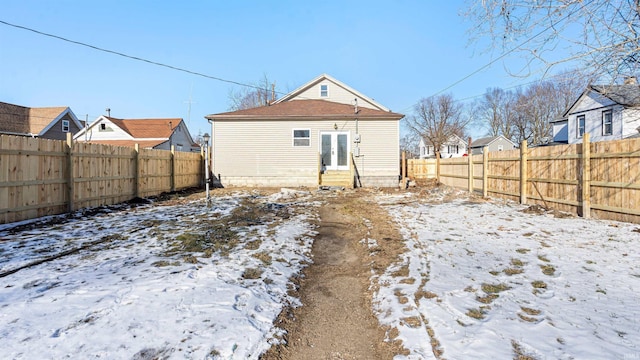 snow covered rear of property with french doors