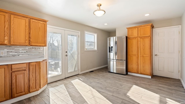 kitchen with backsplash, stainless steel fridge, french doors, and a healthy amount of sunlight