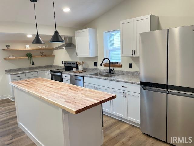 kitchen with sink, stainless steel appliances, a kitchen island, butcher block countertops, and white cabinets