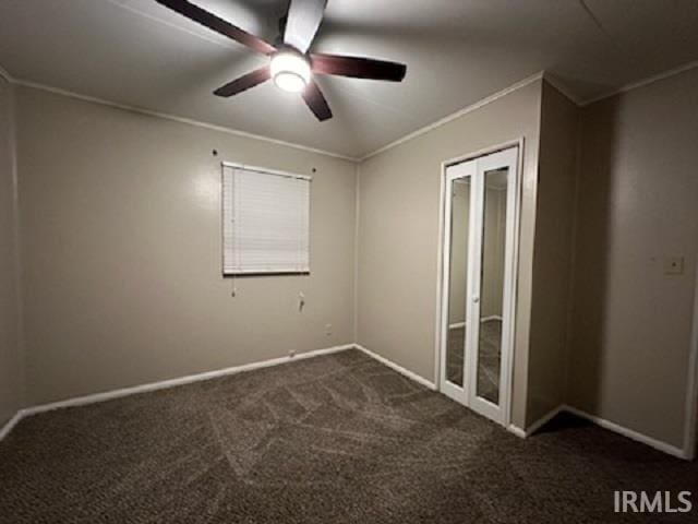 spare room with ceiling fan, ornamental molding, and dark colored carpet