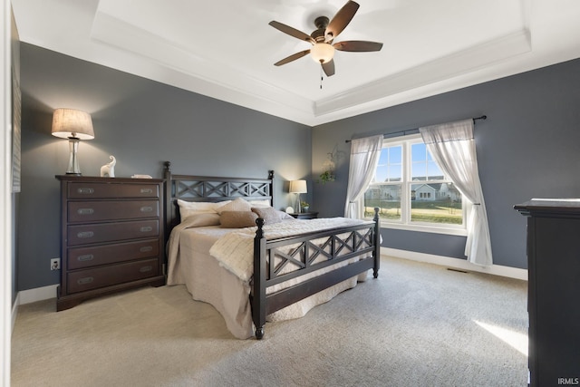 carpeted bedroom with a tray ceiling and ceiling fan