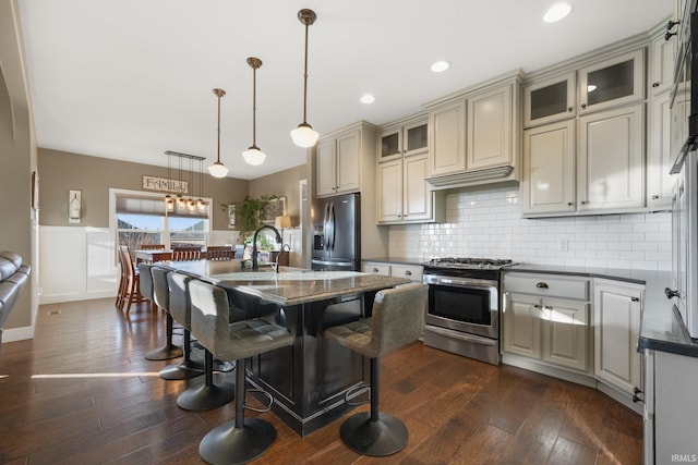 kitchen with stainless steel appliances, sink, pendant lighting, a center island with sink, and dark hardwood / wood-style floors