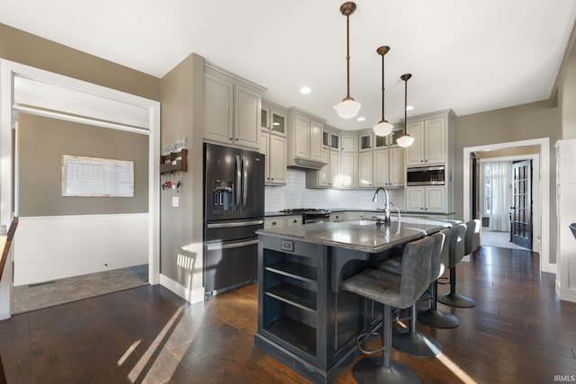 kitchen featuring stainless steel microwave, a kitchen island with sink, sink, hanging light fixtures, and black fridge with ice dispenser