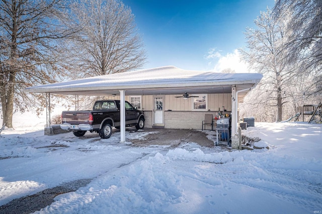 snow covered parking area featuring a carport