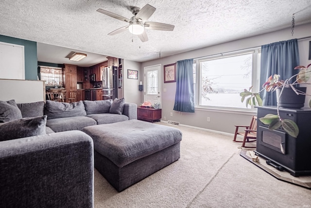 carpeted living room featuring ceiling fan, a wood stove, and a textured ceiling