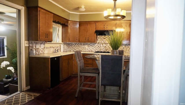 kitchen featuring pendant lighting, backsplash, dark wood-type flooring, ceiling fan with notable chandelier, and sink