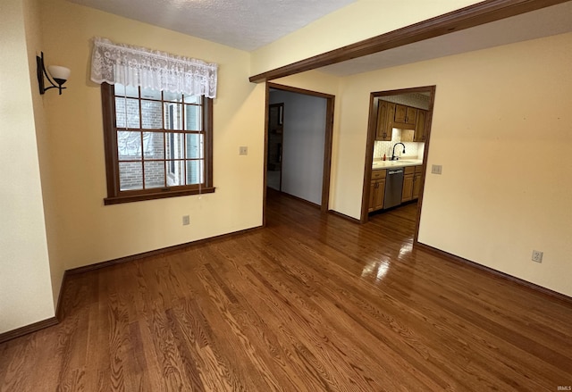 unfurnished room featuring a textured ceiling, dark hardwood / wood-style floors, and sink