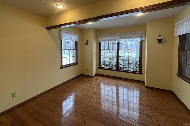 empty room with hardwood / wood-style floors and a textured ceiling