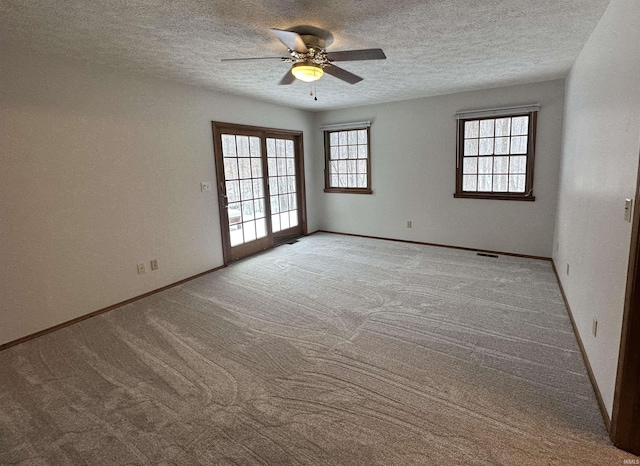 empty room with ceiling fan, light colored carpet, a textured ceiling, and a wealth of natural light