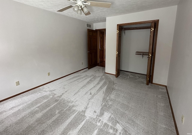 unfurnished bedroom with ceiling fan, light colored carpet, a textured ceiling, and a closet