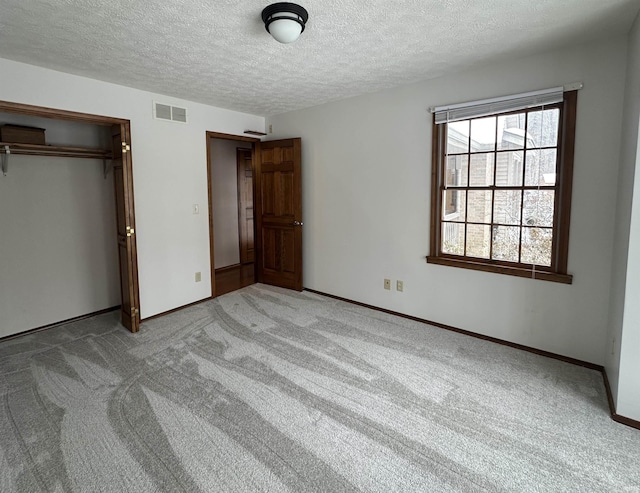 unfurnished bedroom featuring light carpet, a textured ceiling, and a closet