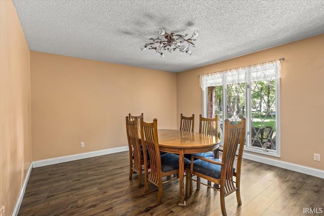 dining room featuring dark wood-type flooring and a textured ceiling