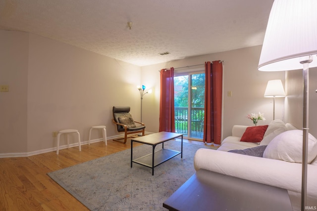 living room featuring wood-type flooring and a textured ceiling