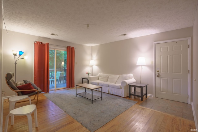 living room with a textured ceiling and light hardwood / wood-style flooring