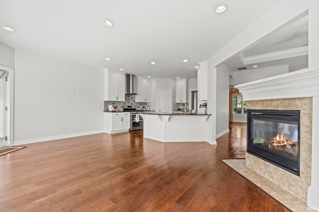 unfurnished living room featuring crown molding, a premium fireplace, sink, and wood-type flooring