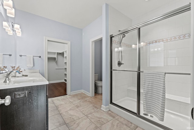 bathroom featuring tile patterned flooring, vanity, toilet, and walk in shower