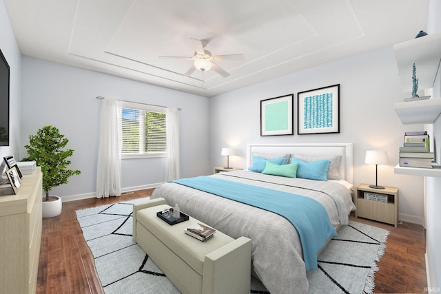 bedroom featuring a raised ceiling, ceiling fan, and dark hardwood / wood-style floors