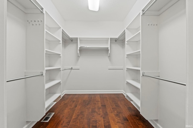 walk in closet with dark wood-type flooring