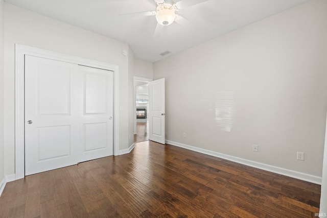 unfurnished bedroom with ceiling fan, dark hardwood / wood-style flooring, and a closet