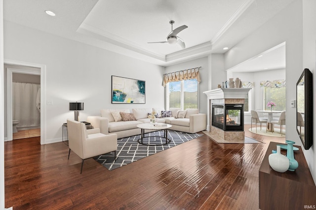 living room with a raised ceiling, ceiling fan, and dark hardwood / wood-style floors