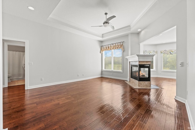 unfurnished living room featuring a raised ceiling, plenty of natural light, and a multi sided fireplace