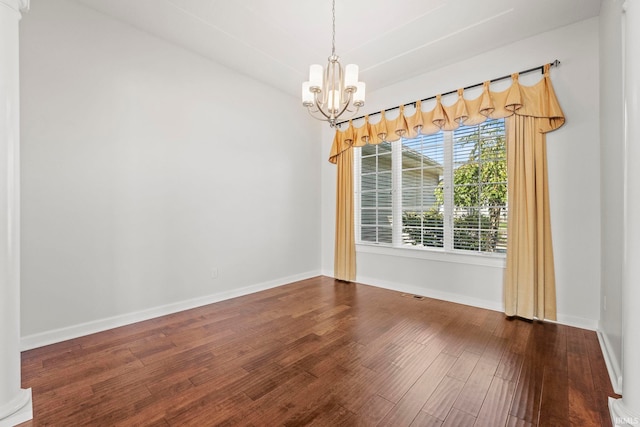 empty room with dark hardwood / wood-style flooring and an inviting chandelier