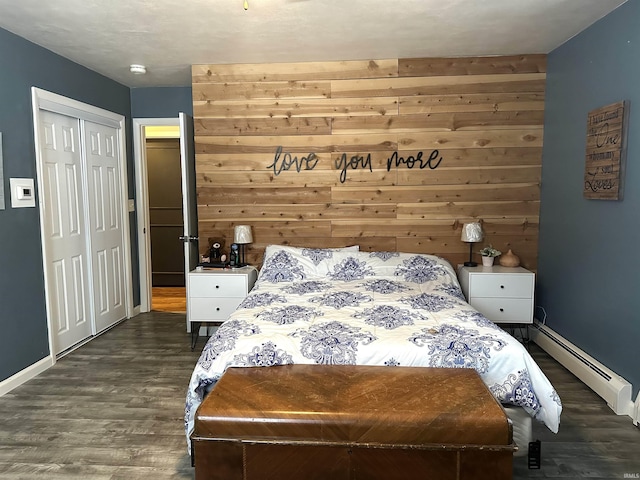 bedroom featuring a closet, baseboard heating, wooden walls, and dark hardwood / wood-style floors