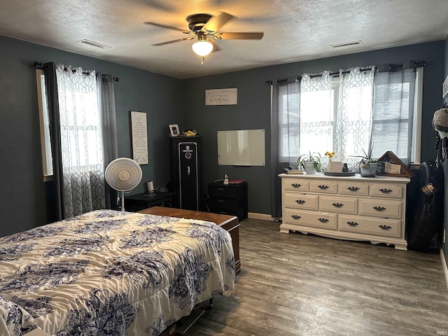 bedroom with multiple windows, a textured ceiling, dark hardwood / wood-style flooring, and ceiling fan