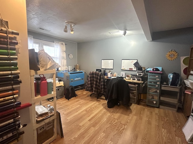 office area featuring light wood-type flooring and a textured ceiling