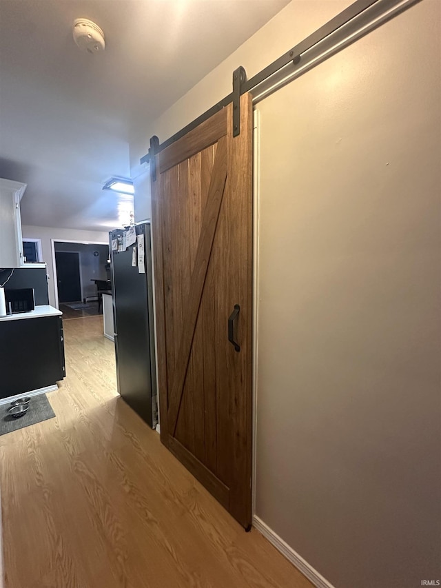 corridor featuring a barn door and light hardwood / wood-style floors