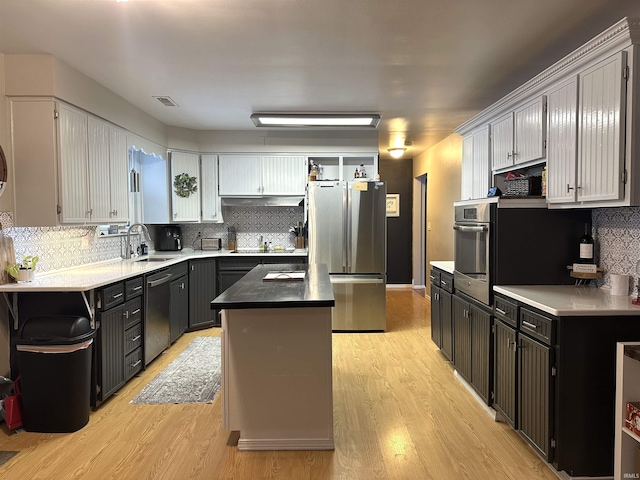 kitchen featuring sink, a kitchen island, stainless steel appliances, and light hardwood / wood-style flooring