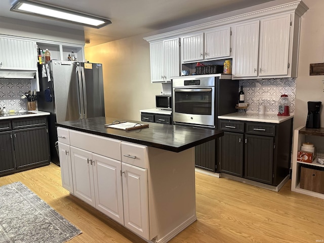 kitchen featuring backsplash, stainless steel appliances, white cabinetry, and a kitchen island