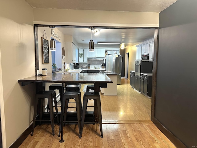 kitchen with kitchen peninsula, decorative backsplash, a breakfast bar, and appliances with stainless steel finishes