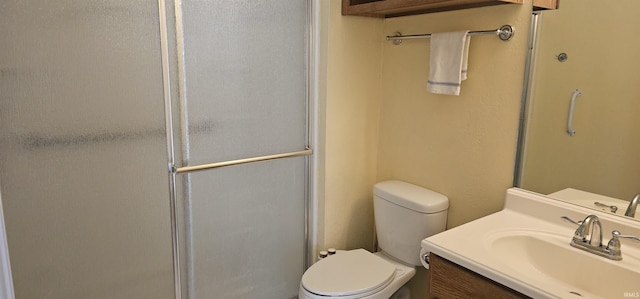 bathroom featuring vanity, toilet, and a shower with shower door