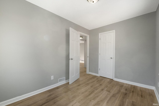 unfurnished bedroom with light wood-type flooring and a closet