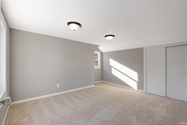 carpeted empty room with lofted ceiling