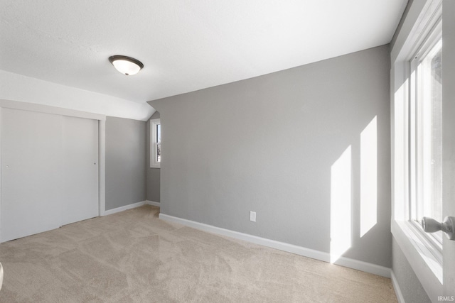 empty room featuring light colored carpet and lofted ceiling