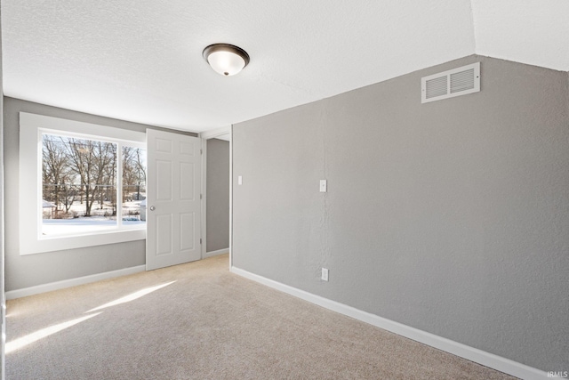 carpeted empty room with a textured ceiling and vaulted ceiling