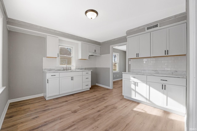 kitchen with decorative backsplash, white cabinetry, sink, and light hardwood / wood-style floors