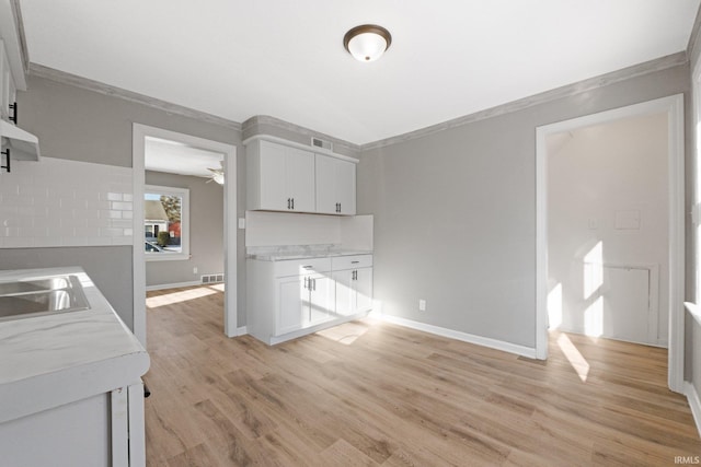 kitchen with sink, light hardwood / wood-style flooring, ceiling fan, ornamental molding, and white cabinetry