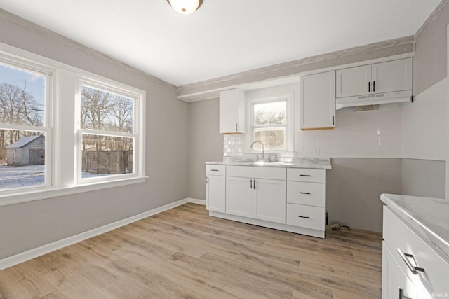 kitchen featuring white cabinets, backsplash, light wood-type flooring, and sink