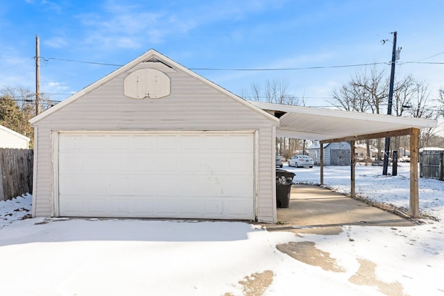 snow covered garage with a carport