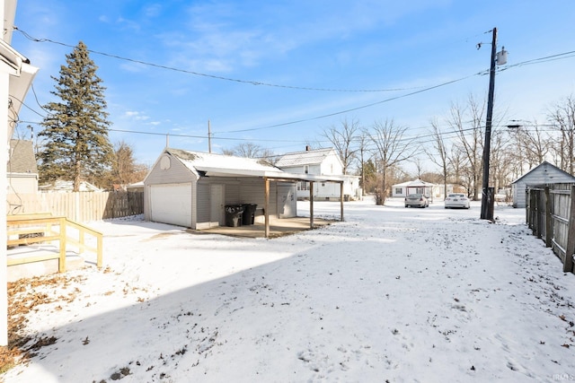 snowy yard featuring a garage and an outdoor structure